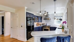 A modern kitchen with a marble countertop, stainless steel appliances, and blue cabinetry. - Waterfront Gem w/ Dock: 2 Mi to Dwtn Annapolis! (Annapolis)