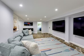 A modern living room with a sectional sofa, a flat-screen TV, and a stone-patterned floor. - Waterfront Gem w/ Dock: 2 Mi to Dwtn Annapolis! (Annapolis)