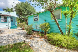 A turquoise mobile home with a stone pathway leading to the entrance, surrounded by greenery and trees. - Walkable Dtwn Spot! Bright Bungalow Near Beach (Lake Worth Beach)