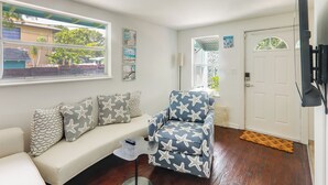 Ein Wohnzimmer mit einer Couch, einem gemusterten Sessel, einem Couchtisch und einer Tür.