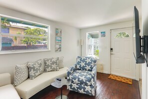 A living room with a sofa, a patterned armchair, a coffee table, and a door. - Walkable Dtwn Spot! Bright Bungalow Near Beach (Lake Worth Beach)