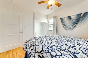 Ein Schlafzimmer mit Bett, Deckenventilator, einem Fenster mit Vorhängen und einer Wandhängematte.