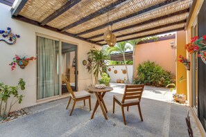Eine überdachte Terrasse mit Tisch und Stühlen, umgeben von Kübelpflanzen und dekorativer Wandgestaltung.