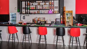 Un espace bar avec un comptoir, de nombreux tabourets et une variété de bouteilles et de verres exposés sur des étagères.