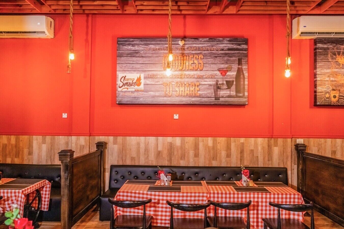 A restaurant interior with red walls, a wooden ceiling, and a large sign above the bar area.