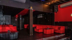 Un salon VIP avec des sièges rouges, un pilier décoratif et un mur étoilé.