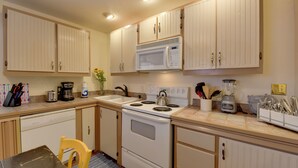 A kitchen with white cabinets, a stove, a microwave, and various appliances. - Charming 1870s Carriage House in Historic Downtown (Savannah)