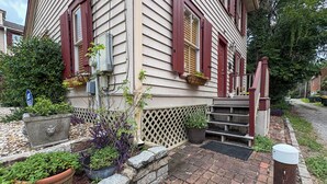 A house with a brick pathway leading to a wooden porch with steps. - Charming 1870s Carriage House in Historic Downtown (Savannah)