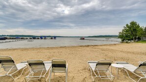 Une plage avec des chaises longues et une jetée où sont amarrés des bateaux.