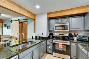 Eine moderne Küche mit Granit Arbeitsplatten, Edelstahlgeräten und Holzbalken.