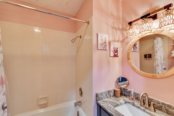 Un bagno con doccia, lavandino, specchio e opere d'arte appese al muro.