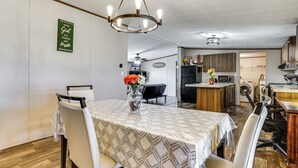 A dining area with a table set for four, a chandelier, and a kitchen in the background. - 9 Mi to Stockyards! Family Home in Fort Worth (Fort Worth)