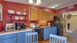 A kitchen with blue cabinets, a stainless steel refrigerator, a coffee maker, and a toaster. - Jasmine Arbor - 2BR Apt in Coveted Historic Dtwn (Savannah)