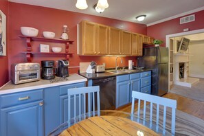 A kitchen with blue cabinets, a stainless steel refrigerator, a coffee maker, and a toaster. - Jasmine Arbor - 2BR Apt in Coveted Historic Dtwn (Savannah)