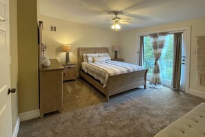 A bedroom with a bed, bedside lamps, a nightstand, a dresser, a ceiling fan, and a sliding glass door to the outside. - Jasmine Arbor - 2BR Apt in Coveted Historic Dtwn (Savannah)
