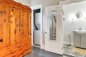 A bathroom with a wooden wardrobe, a washing machine, a mirror, and a sink. - Mid-Term Stay in Mobile! Charming Retreat w/ Deck (Mobile)