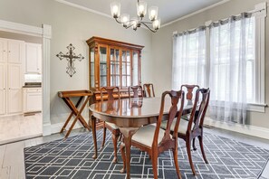A dining room with a wooden table and chairs, a chandelier, a wooden cabinet, and a cross on the wall. - Mid-Term Stay in Mobile! Charming Retreat w/ Deck (Mobile)