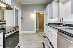 A kitchen with a stainless steel range, a double sink, and a wooden door leading to another room. - Mid-Term Stay in Mobile! Charming Retreat w/ Deck (Mobile)