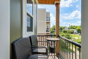 A balcony with wicker chairs and a small table, overlooking a residential area with houses and greenery. - 4 Mi to Broadway: Chic Townhome w/ Home Office! (Nashville)