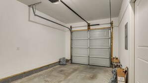 A garage with a closed garage door, concrete floor, and a power outlet on the wall.