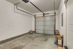 A garage with a closed garage door, concrete floor, and a power outlet on the wall. - 4 Mi to Broadway: Chic Townhome w/ Home Office! (Nashville)