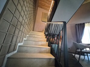 A staircase with a geometric wall design, a modern railing, and a dining area with a table and chairs.
