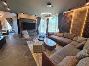A modern living room with a sofa, ottoman, and a flat-screen TV.