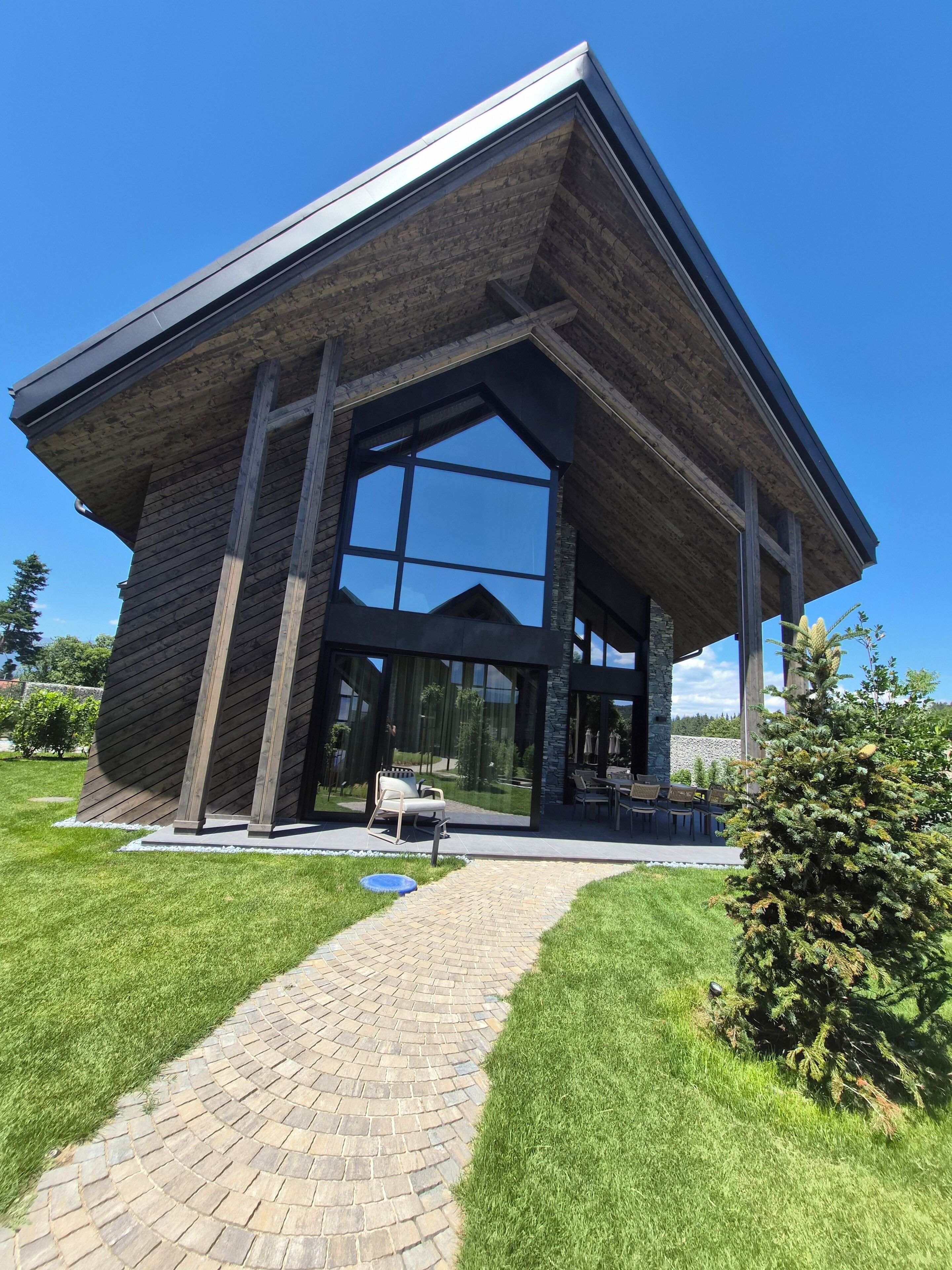 A modern building with a brick facade, large glass windows, and a paved entrance.