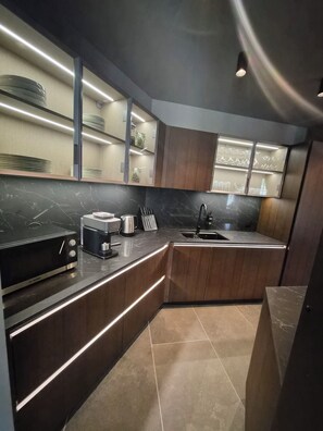 A modern kitchen with a built-in oven, a coffee maker, and a sink.