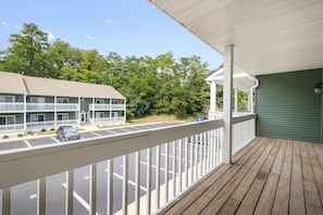 A wooden deck with a view of a motel and parking lot. - Luxury 2BR/2BA Condo |Walk to ND| Private Balcony (South Bend)