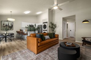 Uma sala de estar moderna com sofá, mesa de centro e área de jantar com cadeiras.