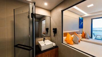 A modern bathroom with a glass shower enclosure, a white sink, and a mirror.