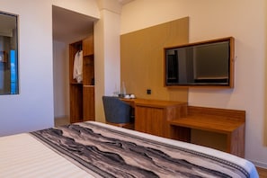 A bedroom with a bed, a desk, a chair, a wardrobe, and a television mounted on the wall. - Triton Exotica (Maafushi)