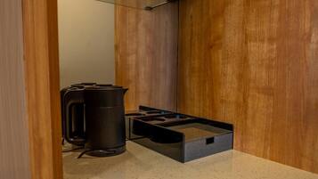 A kitchenette with a gas stove, a kettle, and a coffee maker.