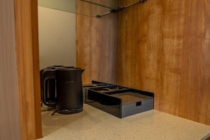 Una kitchenette equipada con estufa a gas, hervidor y cafetera.