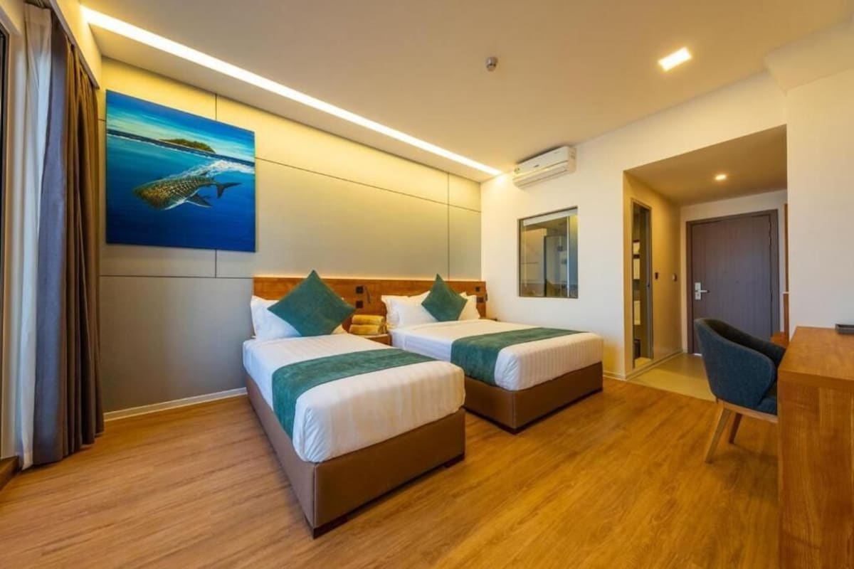 Habitación de hotel con dos camas, un escritorio y un cuadro de un pez en la pared.