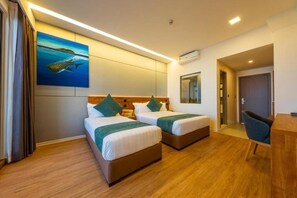 Habitación de hotel con dos camas, un escritorio y un cuadro de un pez en la pared.