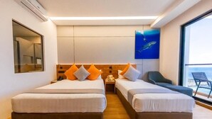 Camera d'albergo con due letti, una grande finestra e un quadro con una balena.