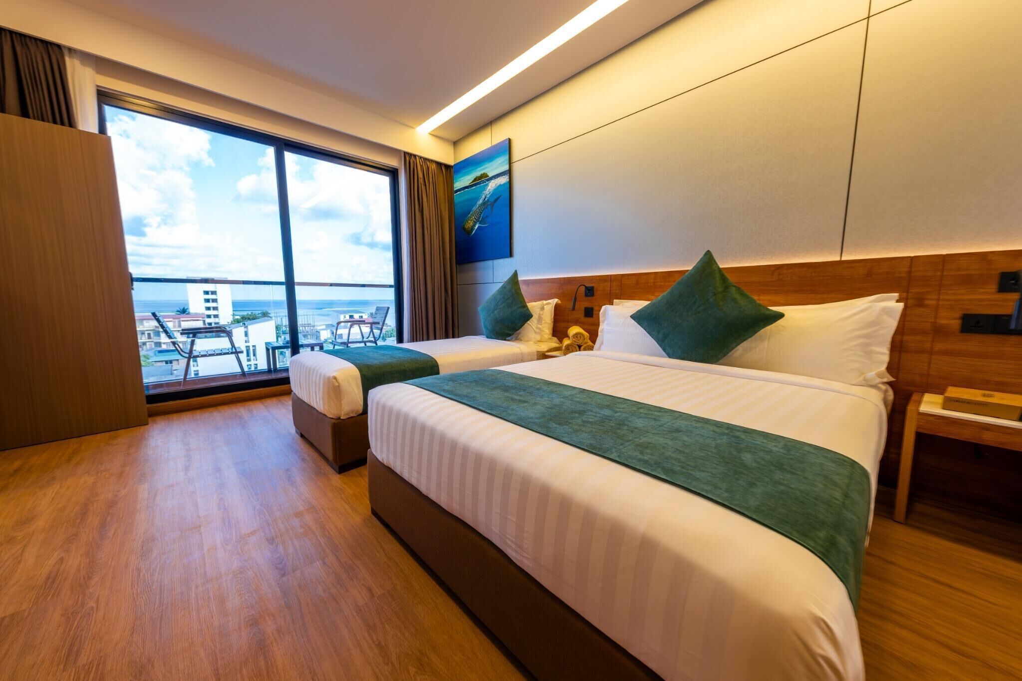 A hotel room with two beds, a large window with a view, and a wooden floor.