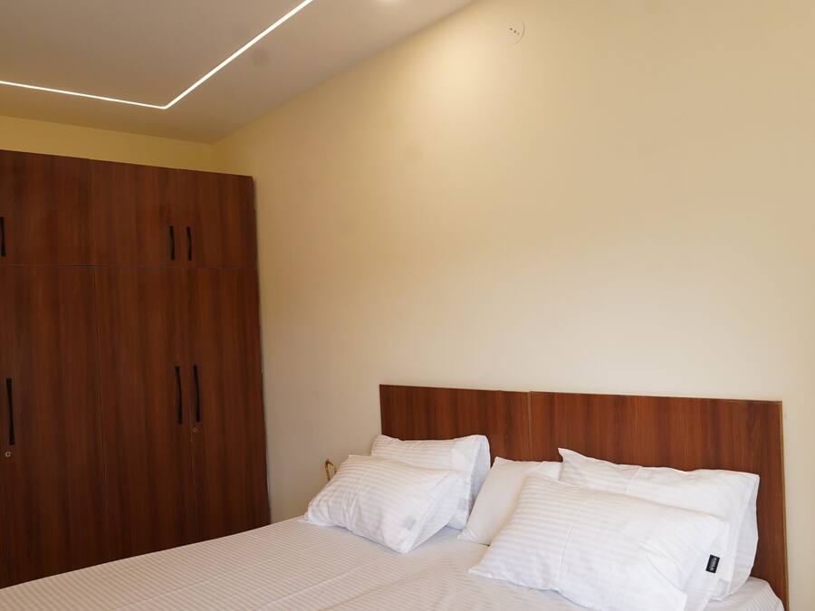 A bedroom with a bed, wooden wardrobe, ceiling fan, and recessed lighting.