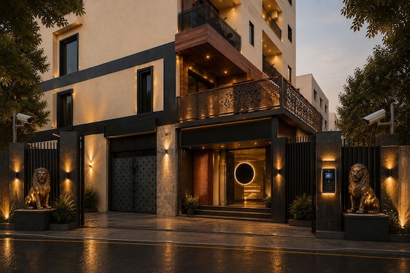 A modern building with a gated entrance, a balcony with intricate railing, and a circular light feature at the entrance.