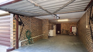 A garage with a brick wall, a washing machine, and a hose. - Surf Sound Holiday Hideaway (WOORIM)