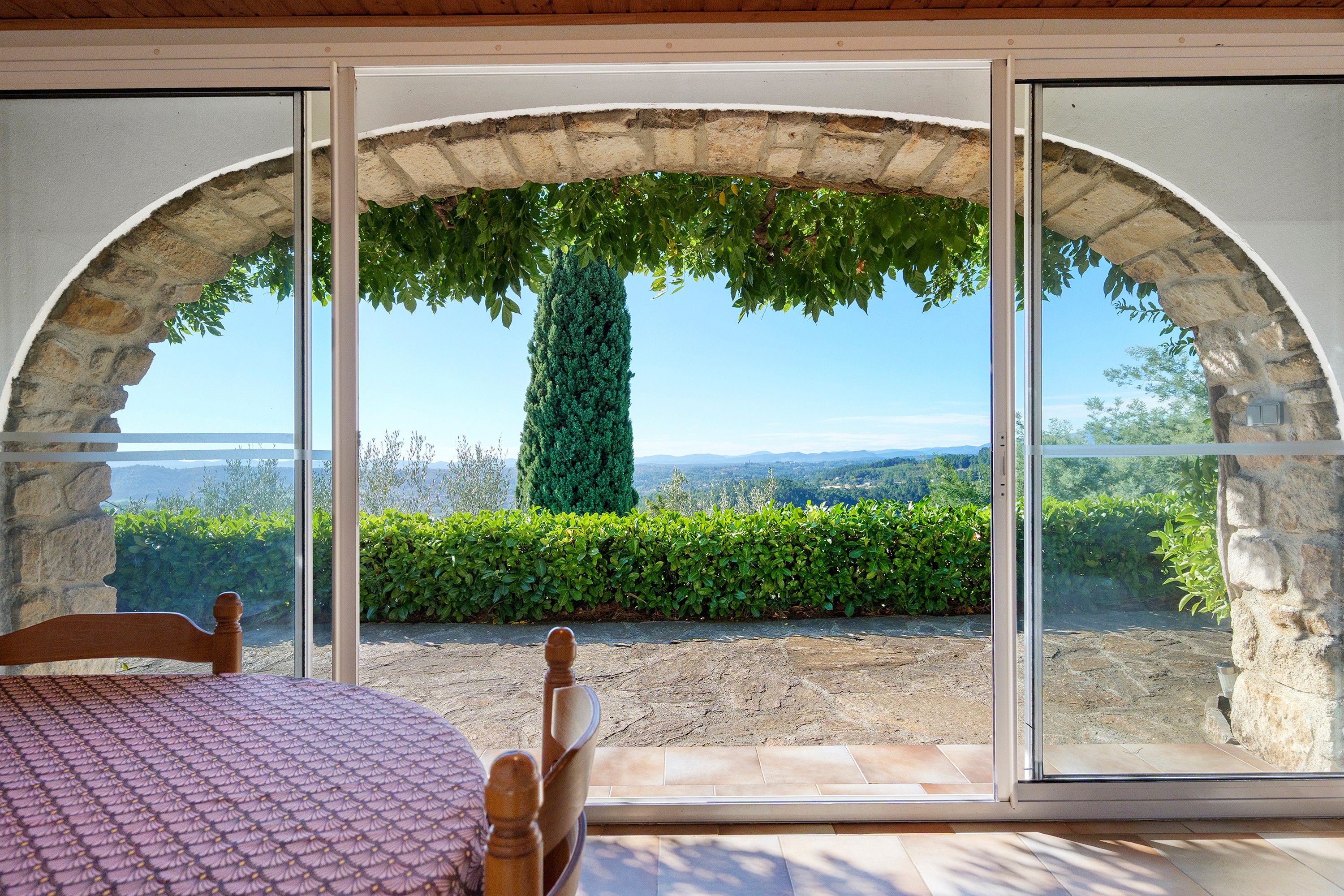 A room with a view through a stone archway, a table, and a chair.