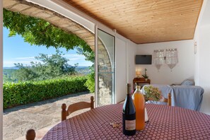 Ein Zimmer mit Tisch, einer Weinflasche und Blick ins Freie.