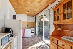 Eine Küche mit Holzbalkendecke, einem Kühlschrank, einem Herd und einem Spülbecken.