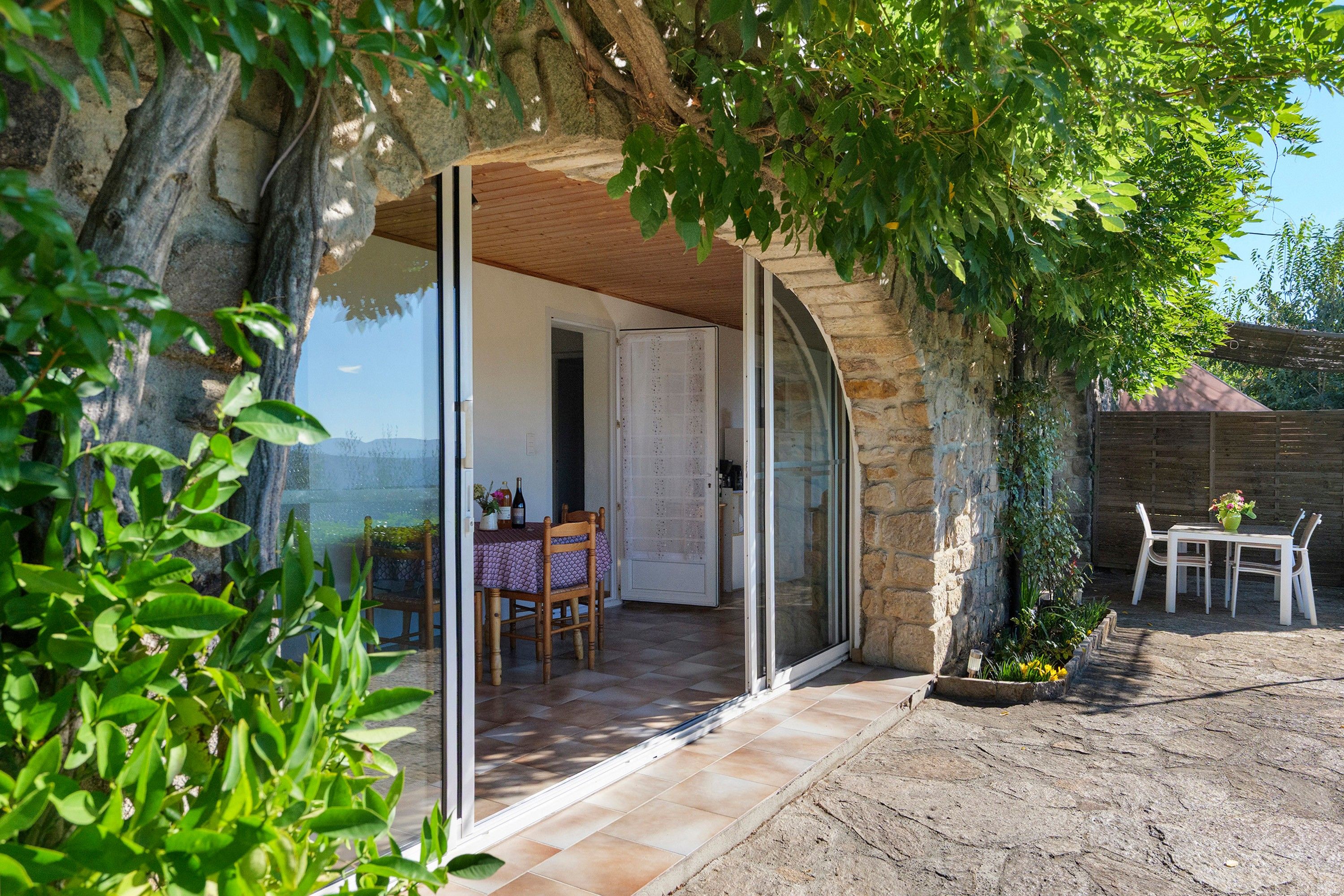 Una casa de piedra con un ventanal de vidrio que da a un comedor con mesa y sillas.