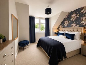 A bedroom with a bed, a dresser, a window with curtains, and a floral wallpaper. - Apartment 91, Inverness (Inverness)