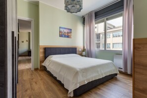 A bedroom with a bed, a painting, a window with curtains, and a hallway. - A bright, modern apartment, recently renovated with high-quality finishes and perfect for accommodating up to four people. The property is located in an elegant neighborhood in the heart of Turin, just 500 meters from Porta Nuova Station—offering direc (Turin)