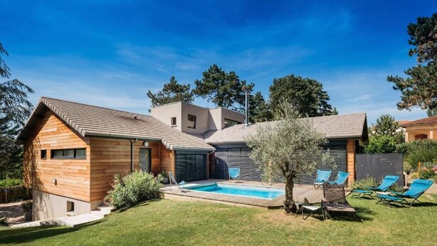 Una casa moderna con piscina, terraza techada y jardín bien cuidado.