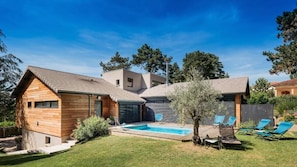 Una casa moderna con piscina, terraza techada y jardín bien cuidado.